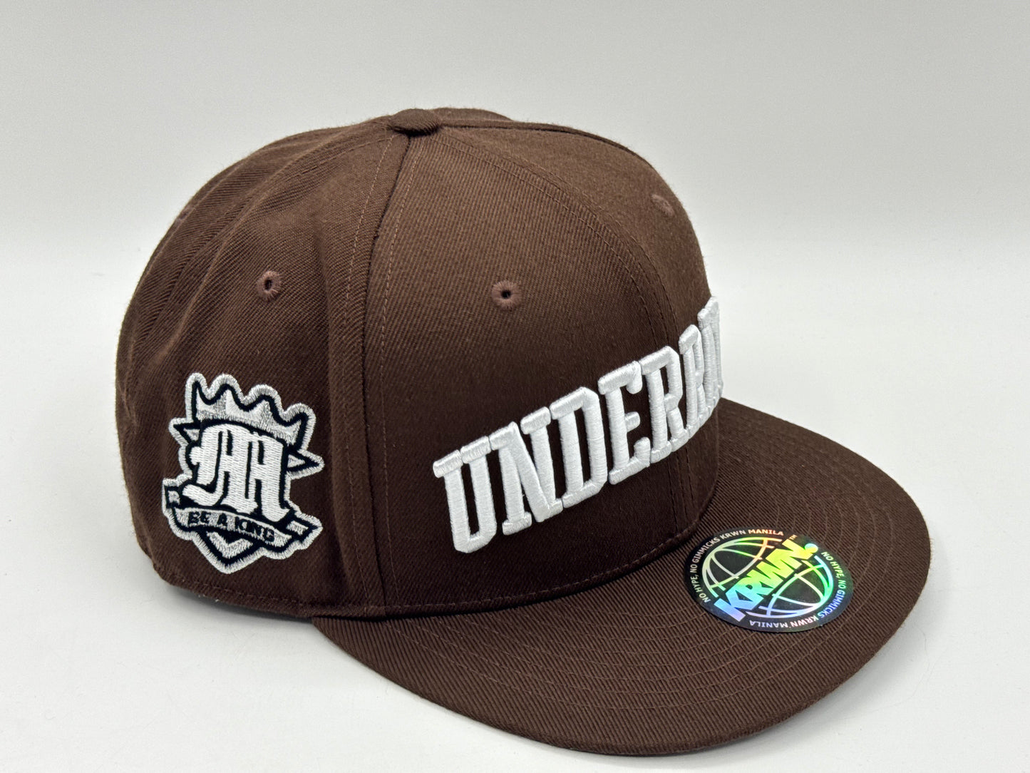 “Underrated” Snapback Cap – Brown by KRWN